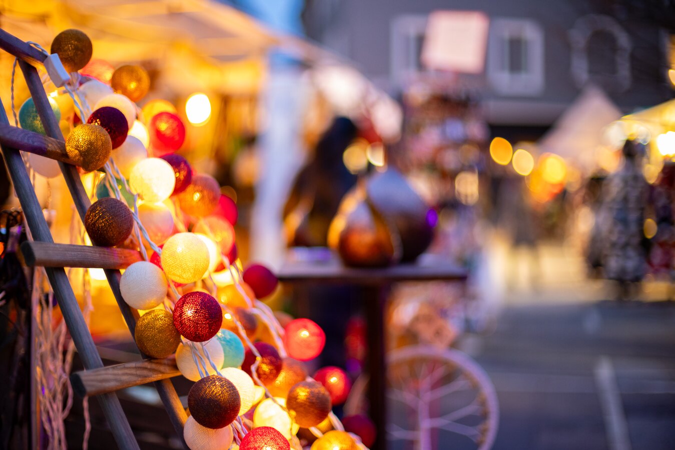 Bunte, leuchtende Baumwollkugeln-Lichterkette auf einem Markt in Graz.