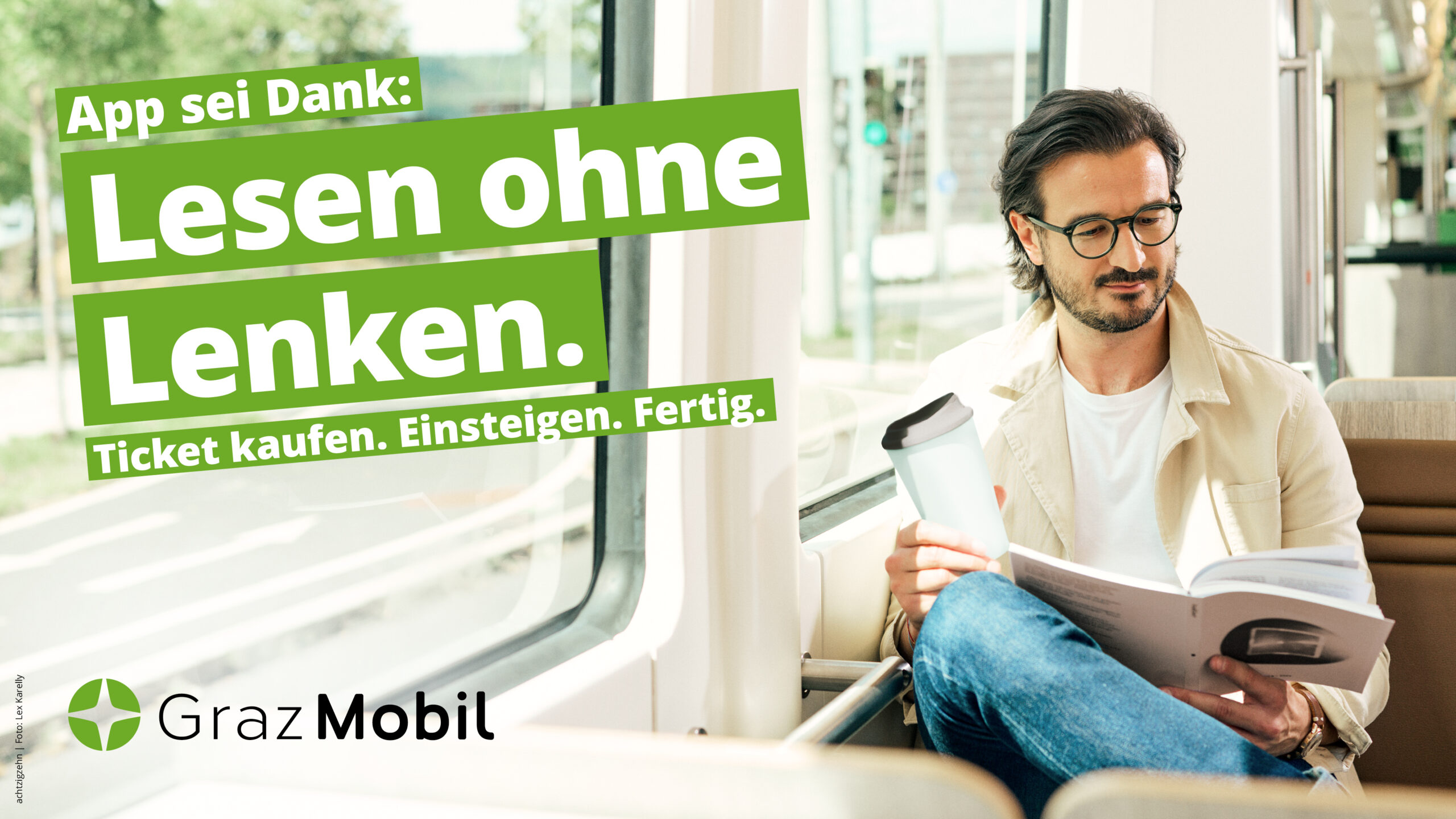 Mann liest in der Graz Mobil Straßenbahn: "Lesen ohne Lenken."