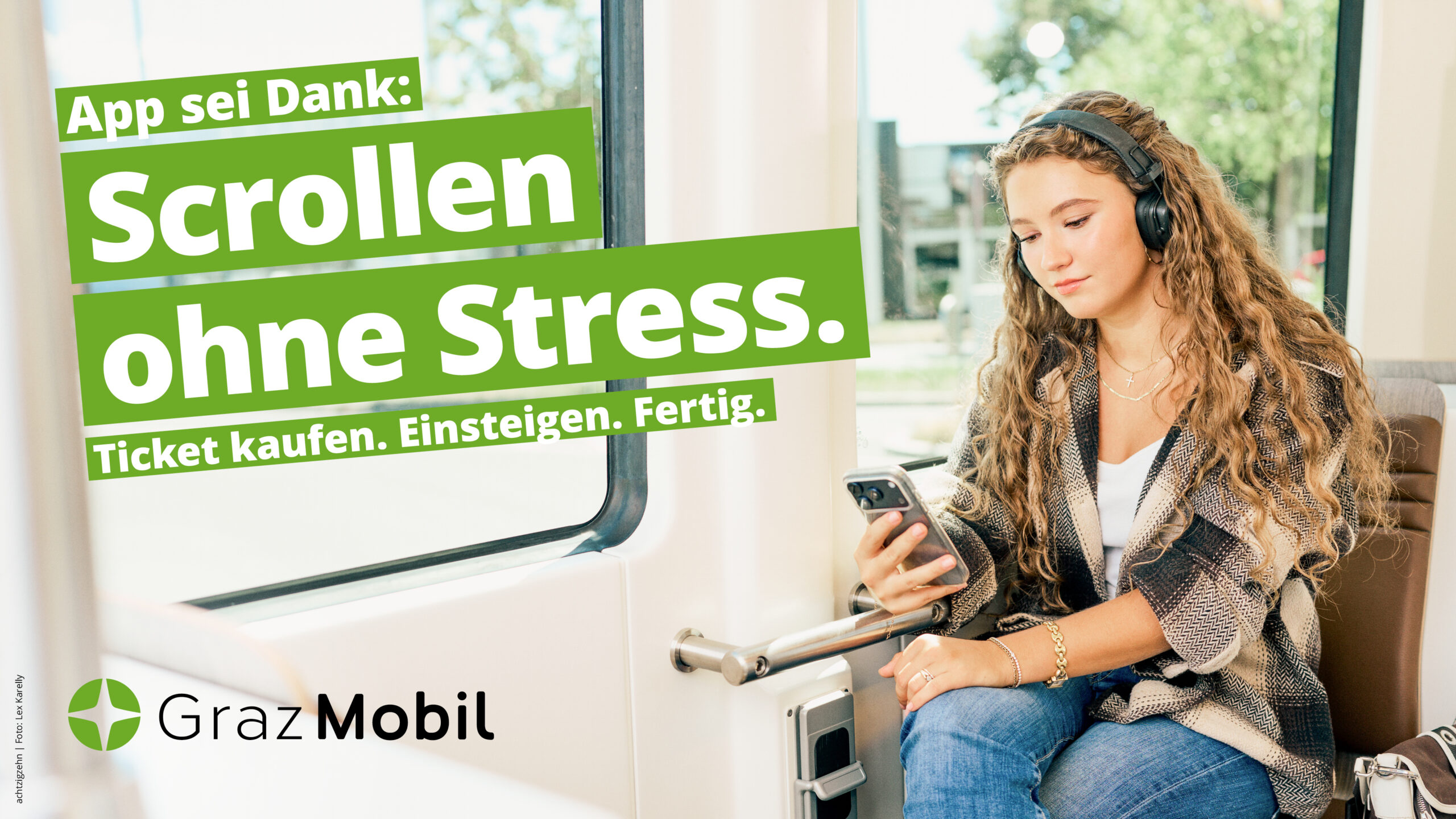 Frau in Bim nutzt Smartphone mit Text: Graz Mobil - Scrollen ohne Stress.
